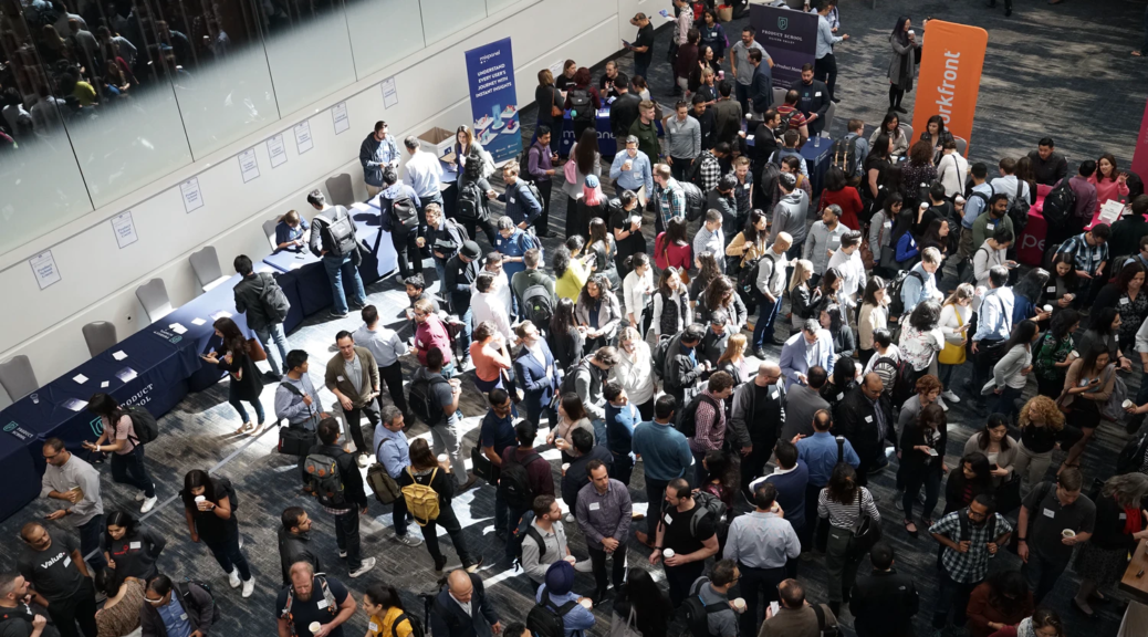 A photograph depicting a large crowd of young people at an event featuring displays by different vendors at tables.