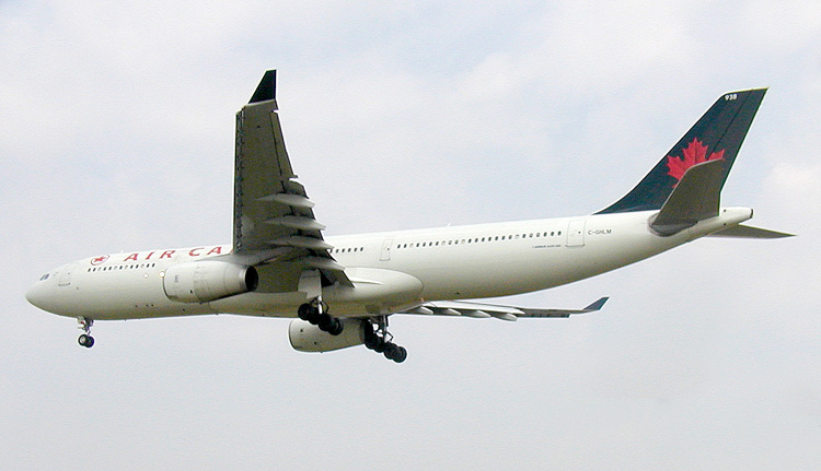 An Air Canada twin-engine jet aircraft flying in front of a cloudy background.